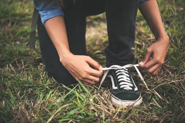 Joven hipster mujer excursionista se detiene para atar su zapato en un hiki de verano — Foto de Stock