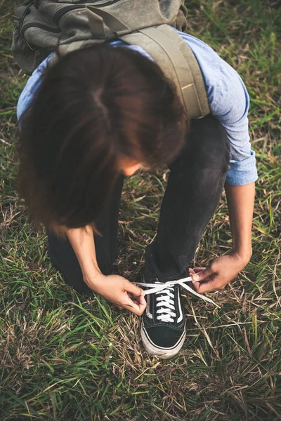 Joven hipster mujer excursionista se detiene para atar su zapato en un hiki de verano — Foto de Stock