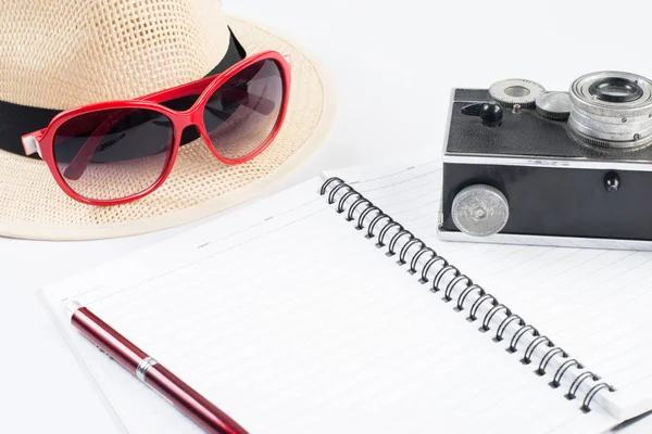 Hat, sunglasses and vintage camera with notepad isolated on a wh