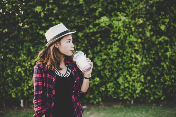 Belle femme hipster boire milkshake debout près de vert t — Photo