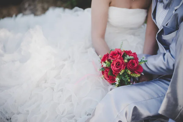 Mariée tient un bouquet de rose rouge de mariage dans les mains, les câlins du marié — Photo