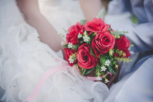 Mariée tient un bouquet de rose rouge de mariage dans les mains, les câlins du marié — Photo