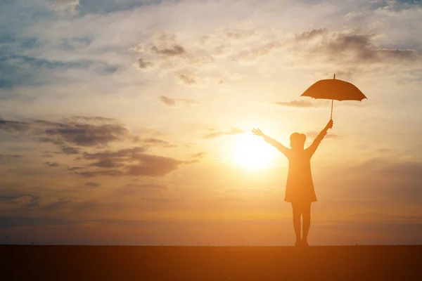 Silhueta de mulher com guarda-chuva no pôr do sol fundo . — Fotografia de Stock