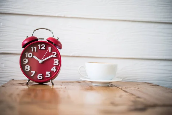 Relógio despertador vermelho com café na mesa de madeira. Hora da pausa para café . — Fotografia de Stock