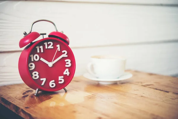 Relógio despertador vermelho com café na mesa de madeira. Hora da pausa para café . — Fotografia de Stock