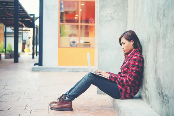 Glad ung hipster kvinna använder sin bärbara dator medan du sitter på den — Stockfoto