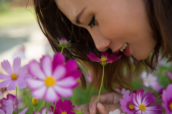 Close up of cheerful woman smelling with cosmos flower at garden — Stock Photo, Image