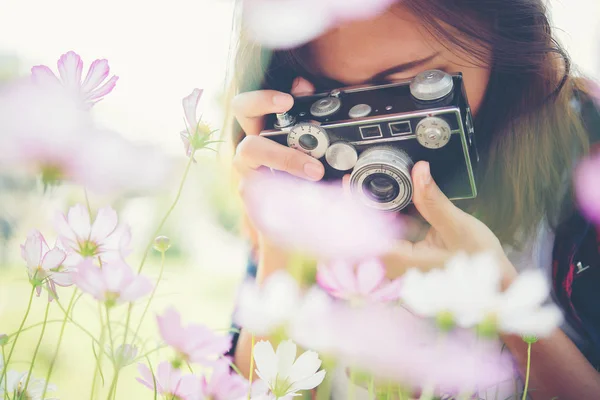 Hipster menina com foco câmera vintage atirando flores em garde — Fotografia de Stock