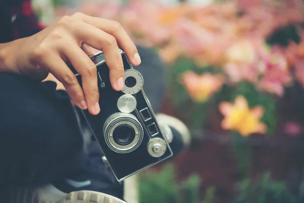 De cerca la mano de la mujer con la cámara vintage enfoque disparar flores — Foto de Stock