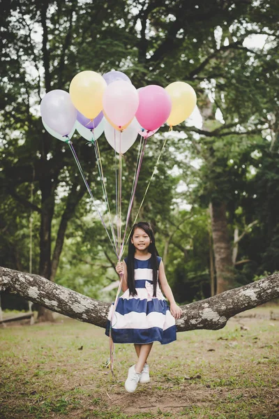 Piccolo carino asiatico ragazza seduta su albero ramo con colorful di b — Foto Stock