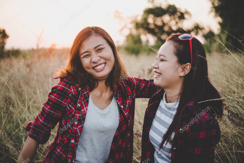 Close up of two girls. Close friends in field with sunset backgr
