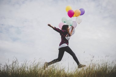 Mutlu hippi kız açık havada renkli oyuncak balonlarla atlama. Genç kadın mavi gök yeşil alandaki eğleniyor. Kadın özgürlük yaşam tarzı kavramı.