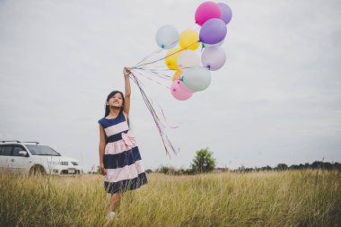Balonlarla meadows sahada oynayan küçük kız.