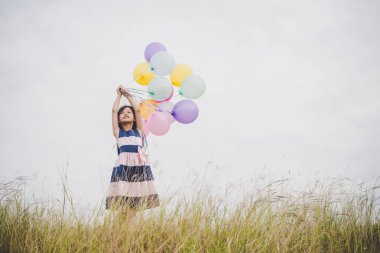 Balonlarla meadows sahada oynayan küçük kız.