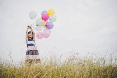 Balonlarla meadows sahada oynayan küçük kız.