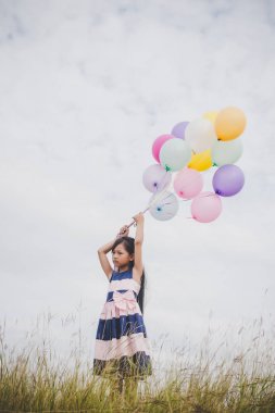 Balonlarla meadows sahada oynayan küçük kız.