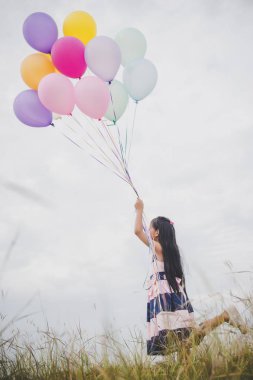 Balonlarla meadows sahada oynayan küçük kız.