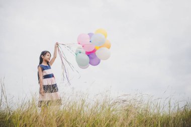 Balonlarla meadows sahada oynayan küçük kız.