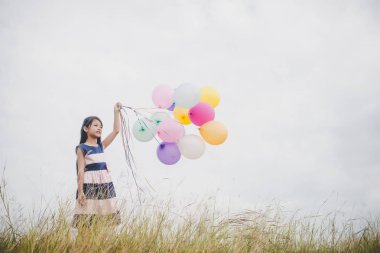 Balonlarla meadows sahada oynayan küçük kız.