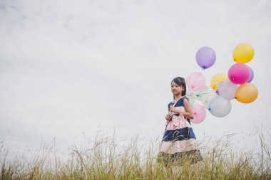 Balonlarla meadows sahada oynayan küçük kız.