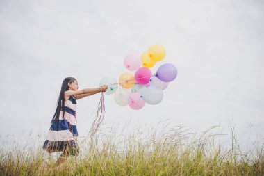 Balonlarla meadows sahada oynayan küçük kız.