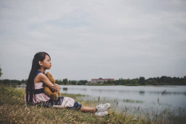 Ayısının meadows sahasında üzmek ile oturan küçük kız.