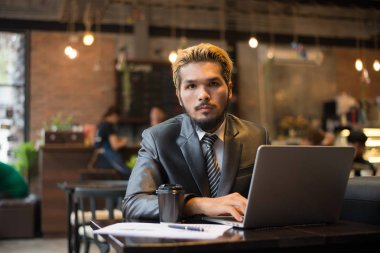 Genç işadamı kahve kafede dizüstü bilgisayarda çalışırken holding.