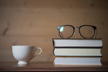 Gözlük kitap yığını ve ahşap masa üzerinde kahve. Eğitim kavramı. 