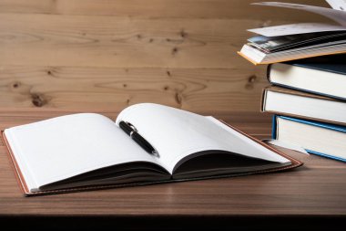Açık kitap, ahşap masa üzerinde ciltli kitap yığını. Eğitim kavramı. Kopya alanı.