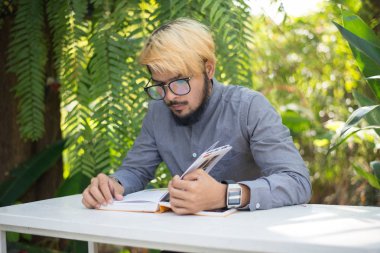 Genç hipster sakal adam ev bahçe doğa ile kitap okuma. Eğitim kavramı.