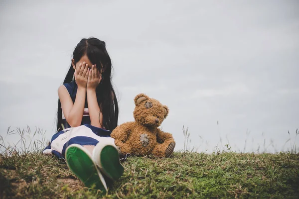 メドウズ フィールドで怒って彼女のクマと座っている少女 — ストック写真