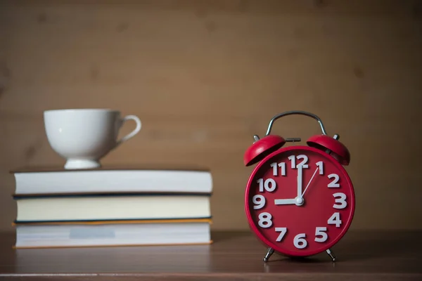 で目覚まし時計と木製のテーブルにコーヒーと書籍のスタック 教育コンセプト — ストック写真