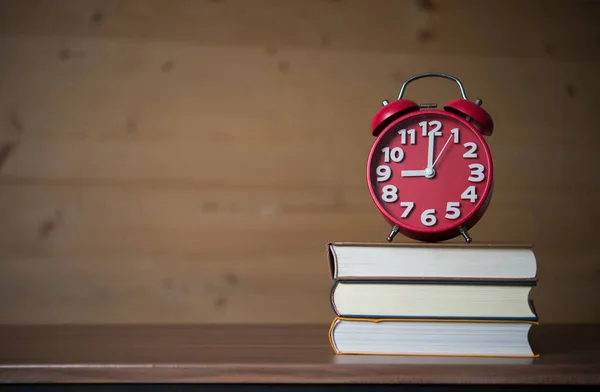 木製のテーブルに書籍のスタックに で目覚まし時計 教育コンセプト — ストック写真