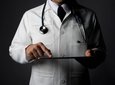 Gri izole bir tablet pc tutan genç tıp doktoru.