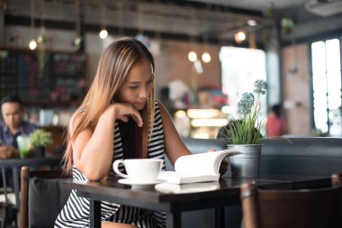 Asyalı kadın rahatlatıcı ve kafede bir kitap okuma. Kadın yaşam tarzı kavramı.