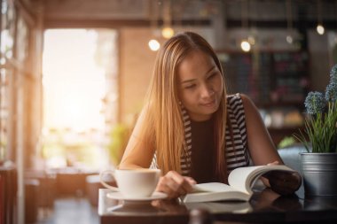 Asyalı kadın rahatlatıcı ve kafede bir kitap okuma. Kadın yaşam tarzı kavramı.