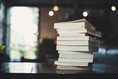 Masa bulanık Kütüphane arka plan üzerinde kitap yığınları.