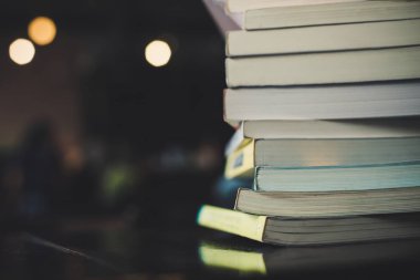 Masa bulanık Kütüphane arka plan üzerinde kitap yığınları.
