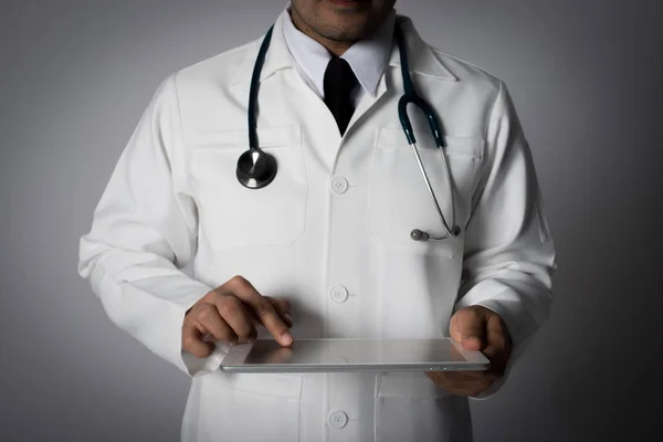 Young medical doctor holding a tablet pc isolated on grey.