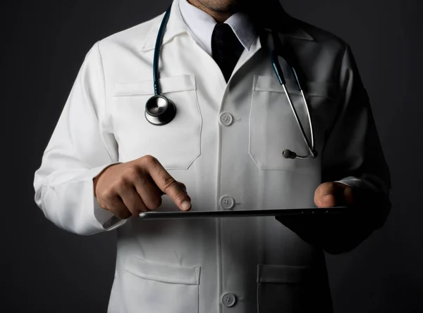Young medical doctor holding a tablet pc isolated on grey.