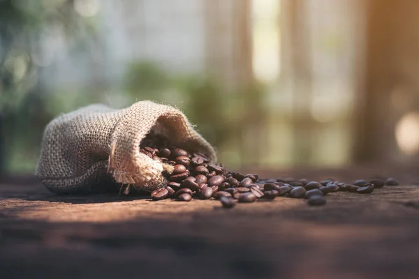 在一个木制的背景上的麻布袋咖啡豆 — 图库照片