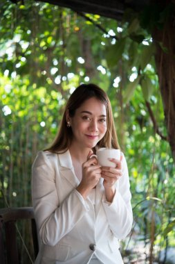 Uzakta mutlu gülümseme, iyi bir hava için memnun ile seyir, işe gitmeden önce kahve ile rahatlatıcı bir genç kadın.