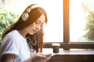 Genç çekici kadın kulaklık pencere arka planda müzik dinleme. Kadın yaşam tarzı kavramı.