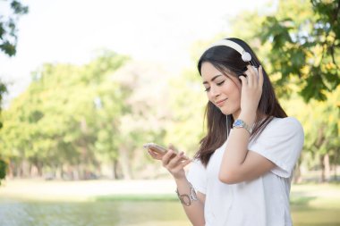 Doğa park mekanlarda dinlenirken müzik kulaklık ile gülümseyen kız portresi.