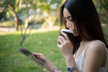 Tek kullanımlık kahve fincanı kısa mesaj yoluyla smartphone vasıl doğa açık havada süre tutan genç güzel kadın.