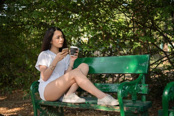 Портрет Счастливой Случайной Женщины Сидящей Скамейке Кофе Смотрящей Телефон Парке — стоковое фото
