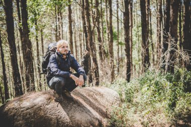 Adam güzel bir doğa etrafında izlerken kayanın üzerine oturmuş dağın zirvesinde. Erkekler yaşam tarzı kavramı.