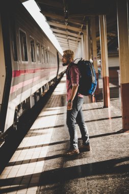 Genç hipster turistik tren istasyonu sırt çantası ile. Tatil turist kavramı.