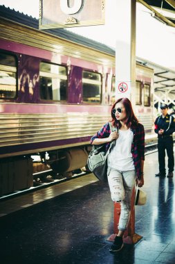 Sırt çantası ile istasyonu platformu üzerinde bekleyen genç hipster kadın. Seyahat kavramı.