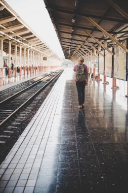 Tren istasyonu yürüyen genç hipster adam. Tren platformu için bekleyen adam. Seyahat kavramı.